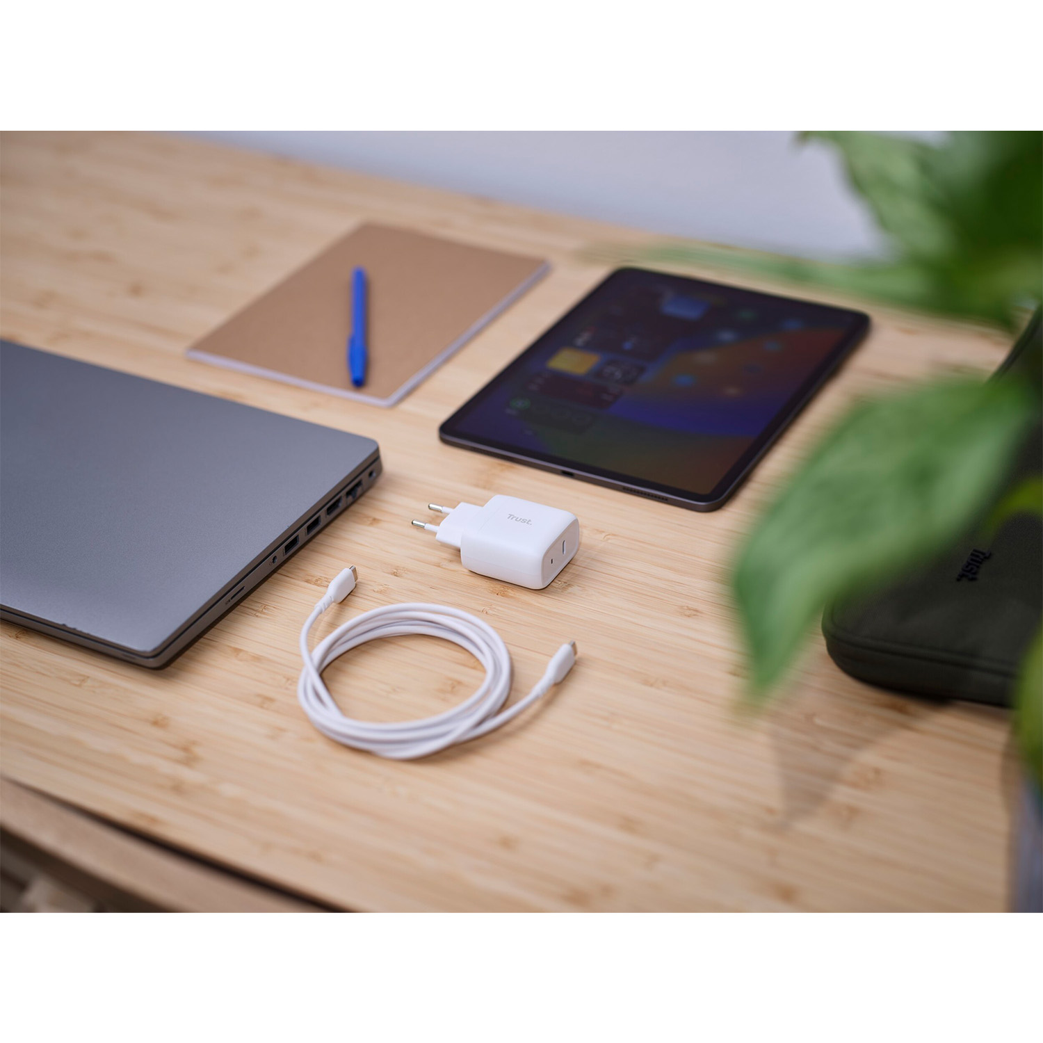 Un laptop, un tablet, un caricabatterie e un cavo su una superficie di legno.