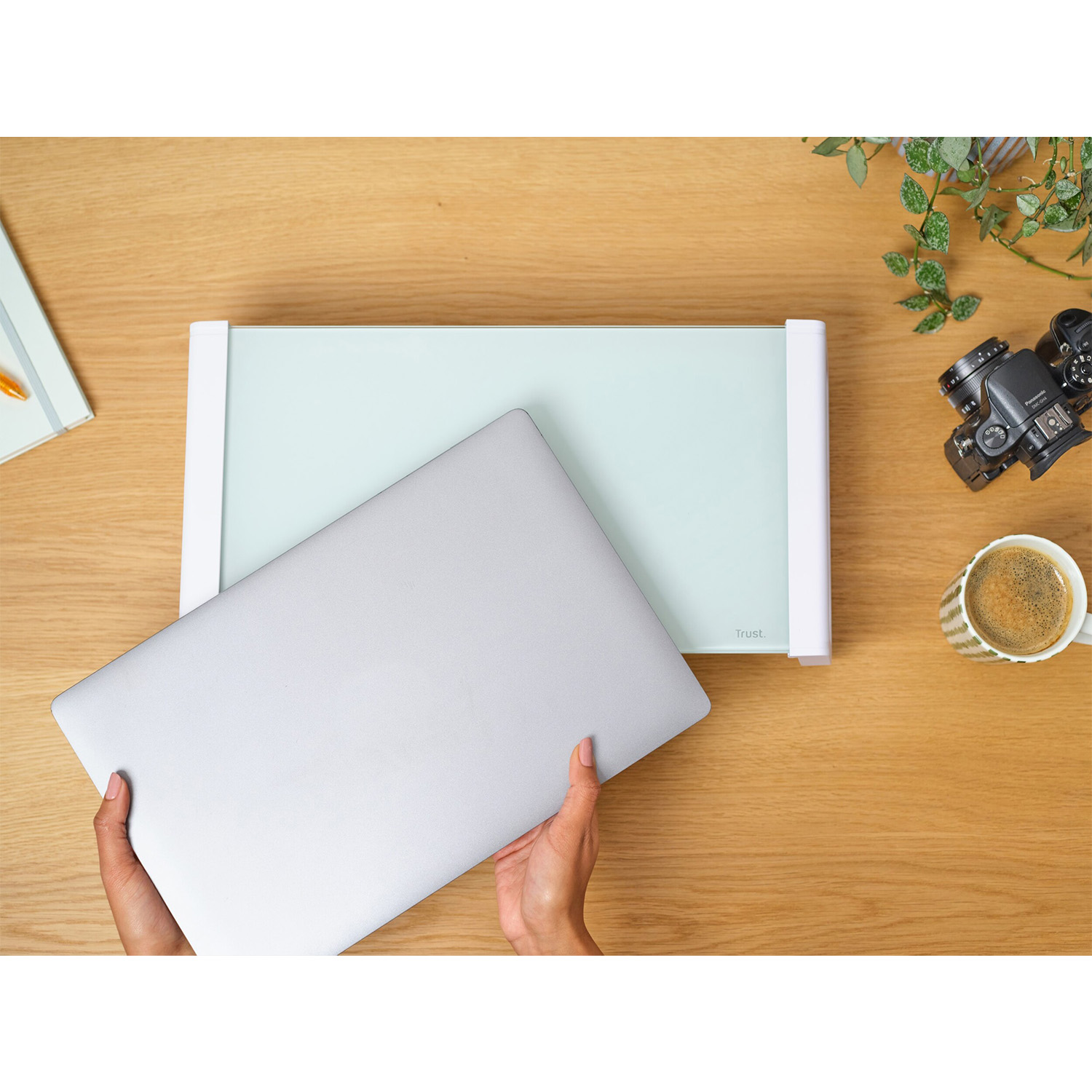 Mani che tengono un laptop vicino a lavagna, fotocamera e tazza di caffè.