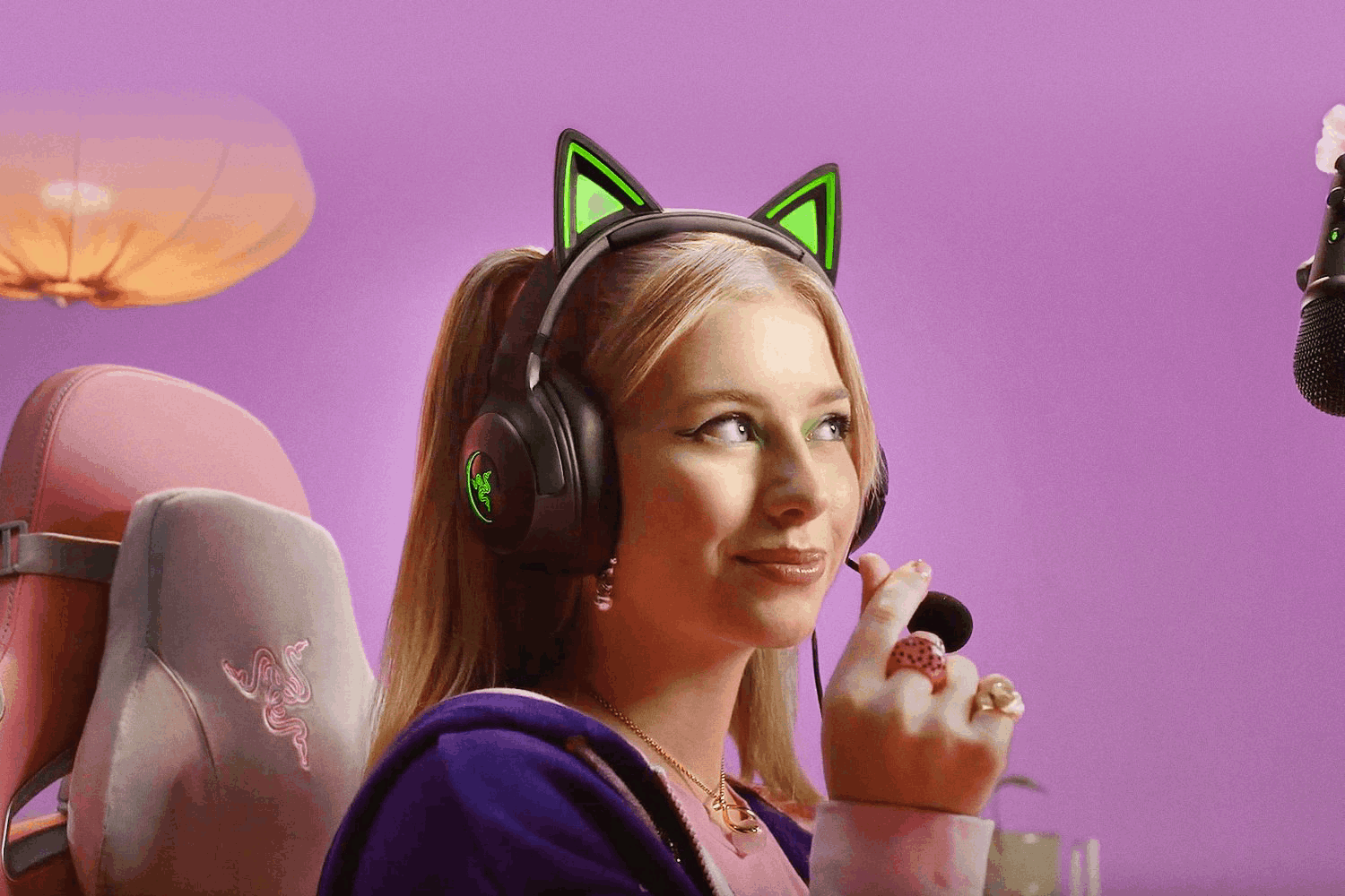 Una joven con auriculares de orejas de gato y micrófono. Sonriendo y mirando a la derecha.