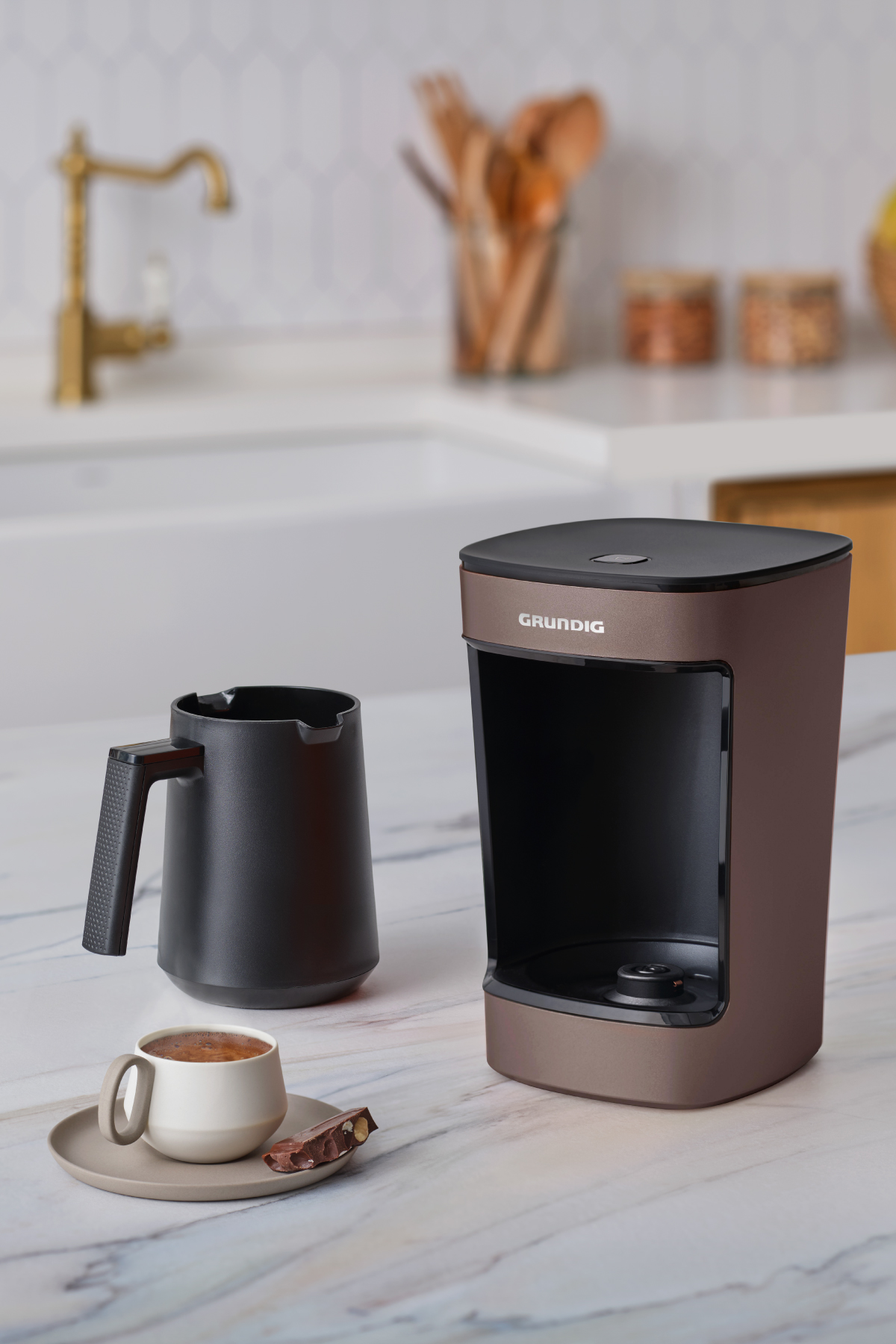 Grundig kahve makinesi ve mermer yüzeyde kahve fincanı, bulanık arka plan.