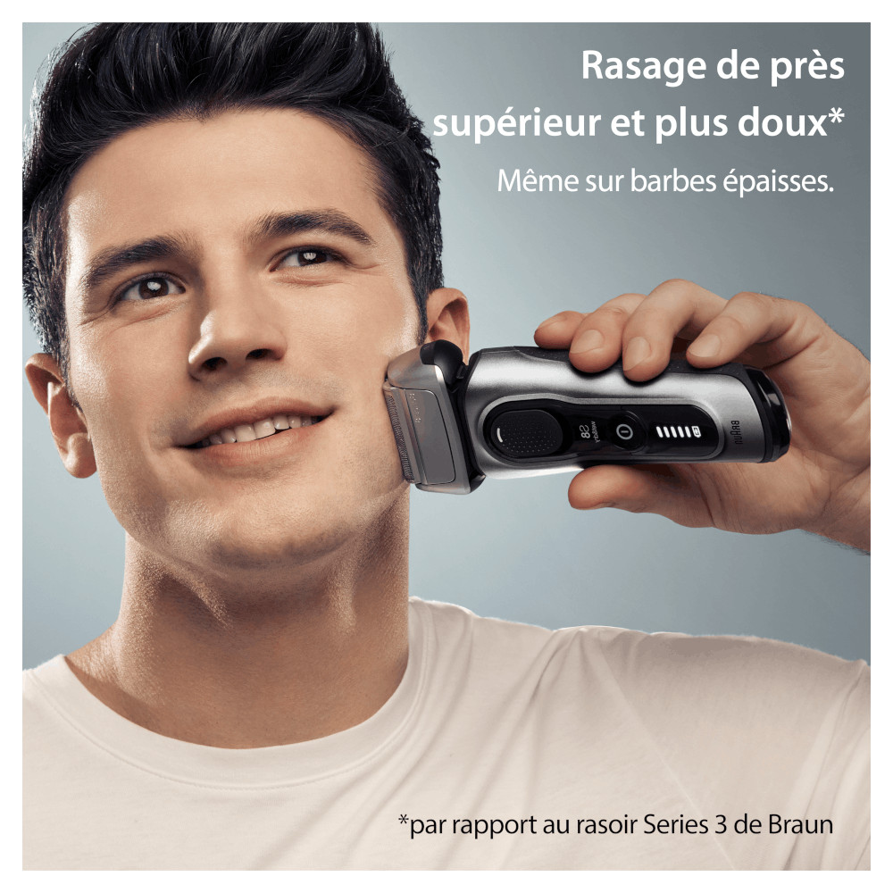 Homme se rasant avec un rasoir électrique argenté, souriant.