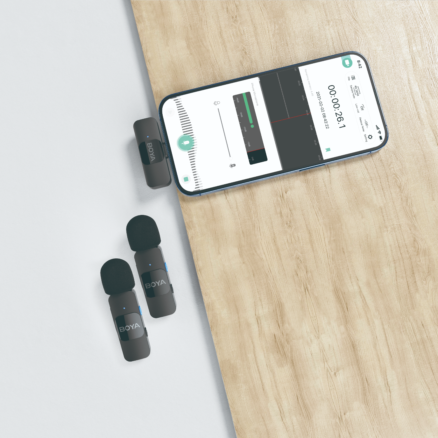 Twee zwarte microfoons en een telefoon die opneemt. De telefoon ligt op hout.