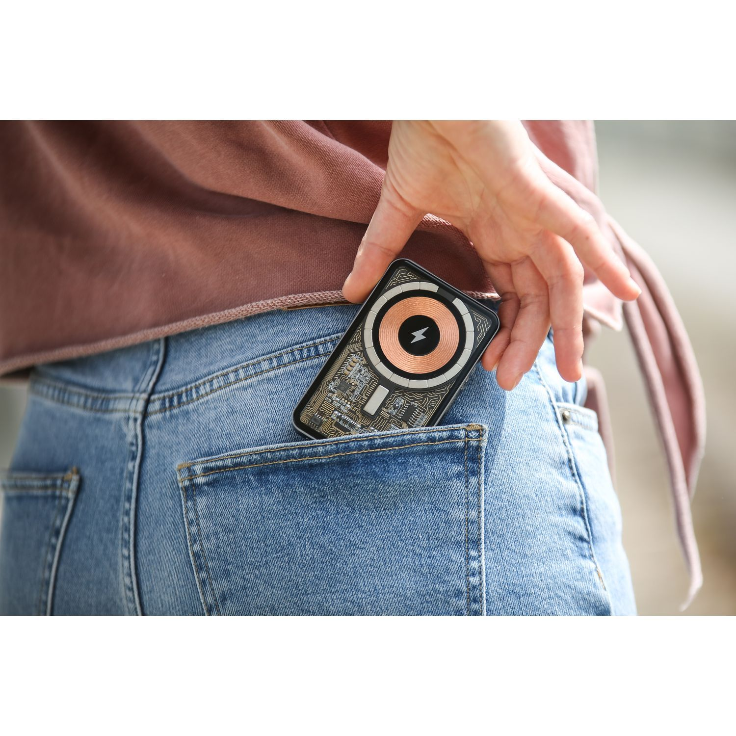 Main mettant un appareil dans une poche de jean.