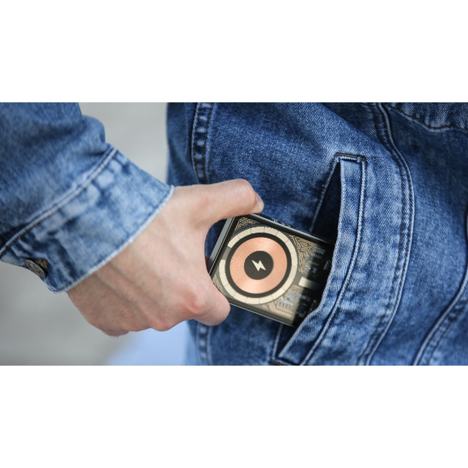 Hand in denim jacket holds a black and copper-colored card in a pocket.