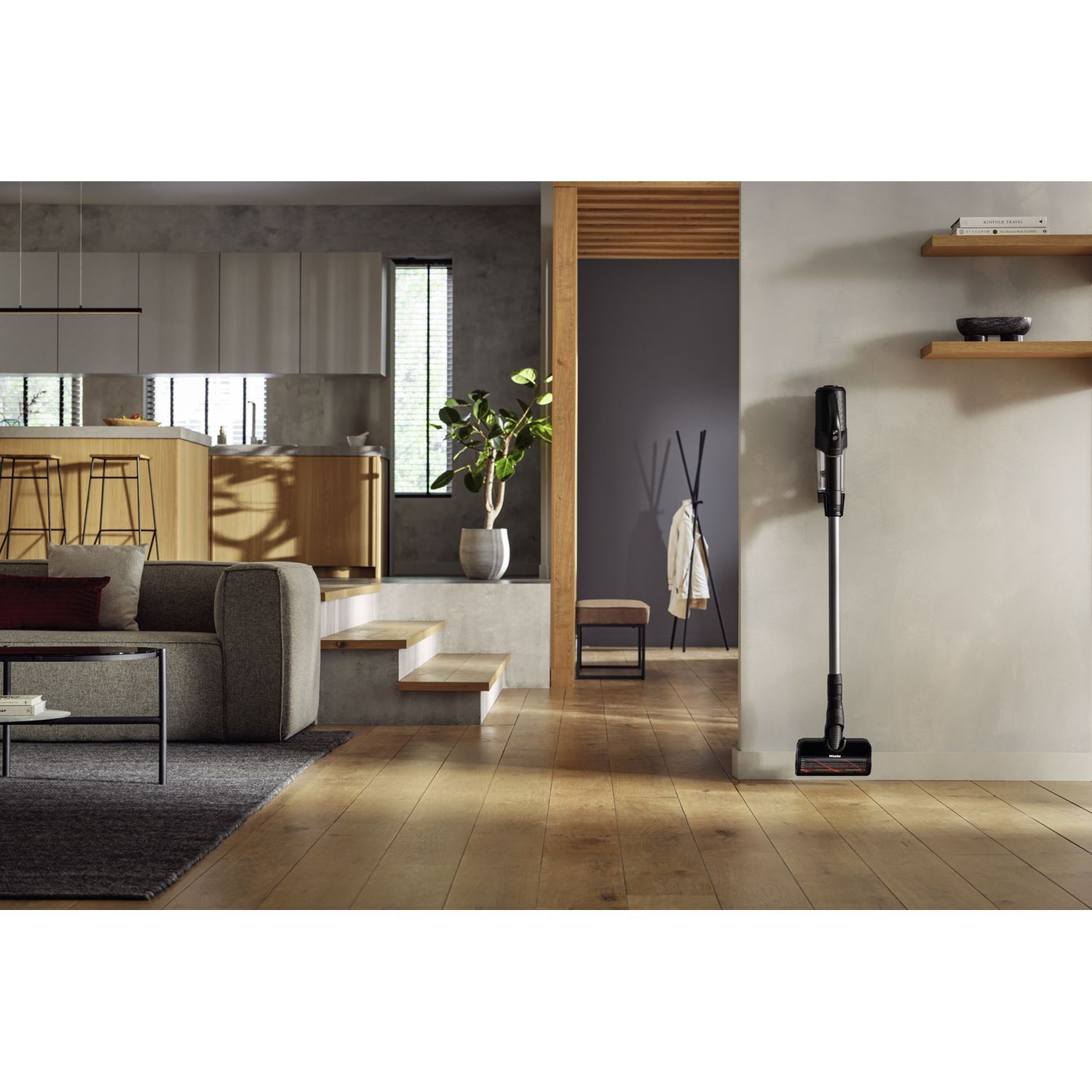 Een moderne woonkamer met een draadloze stofzuiger aan de muur en een bank.