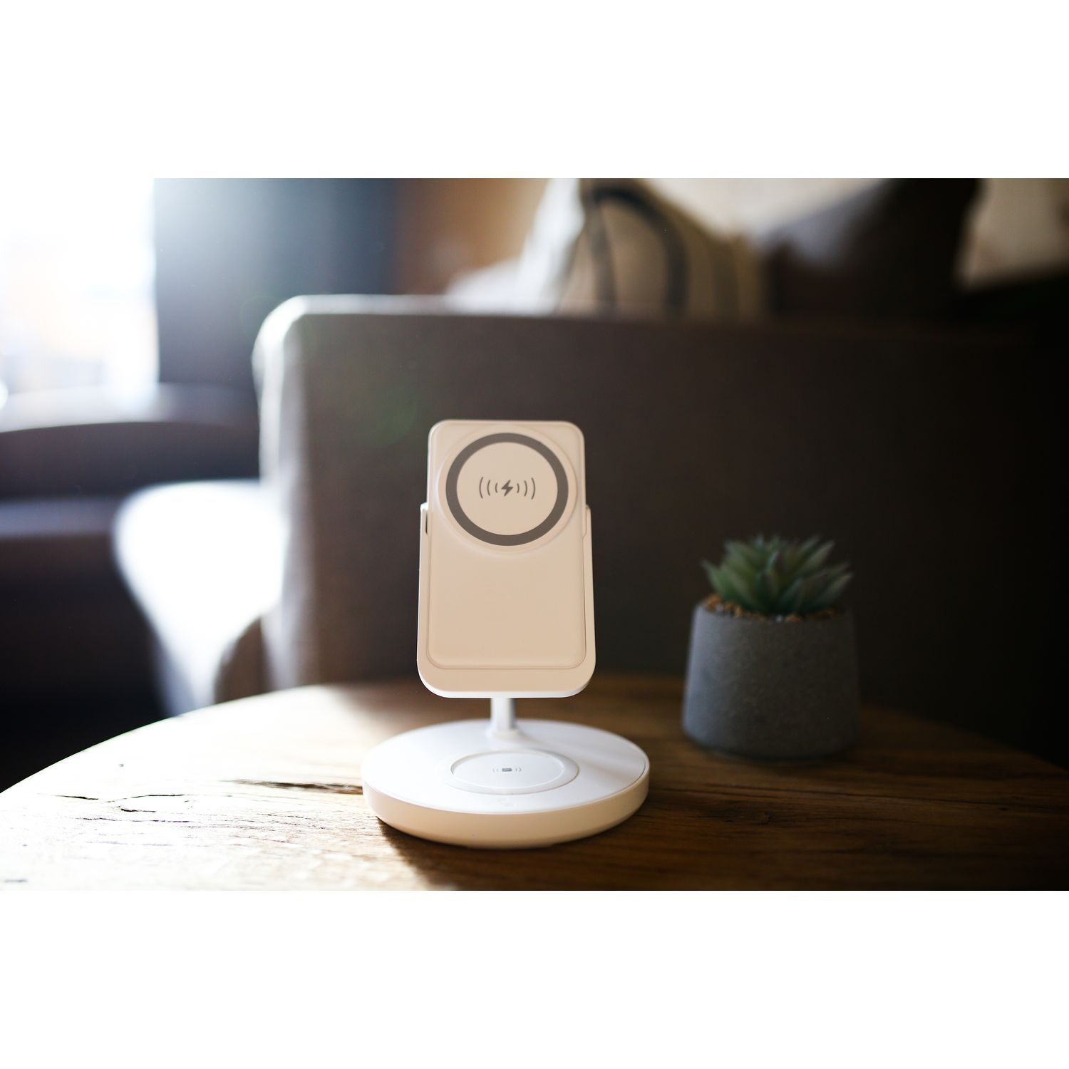 Un chargeur de téléphone blanc avec un téléphone dessus, sur une table en bois.