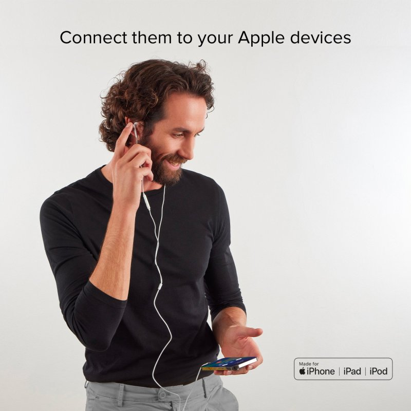 Mann mit schwarzem Hemd hält weiße Kopfhörer, die mit einem Telefon verbunden sind. Lächelt.
