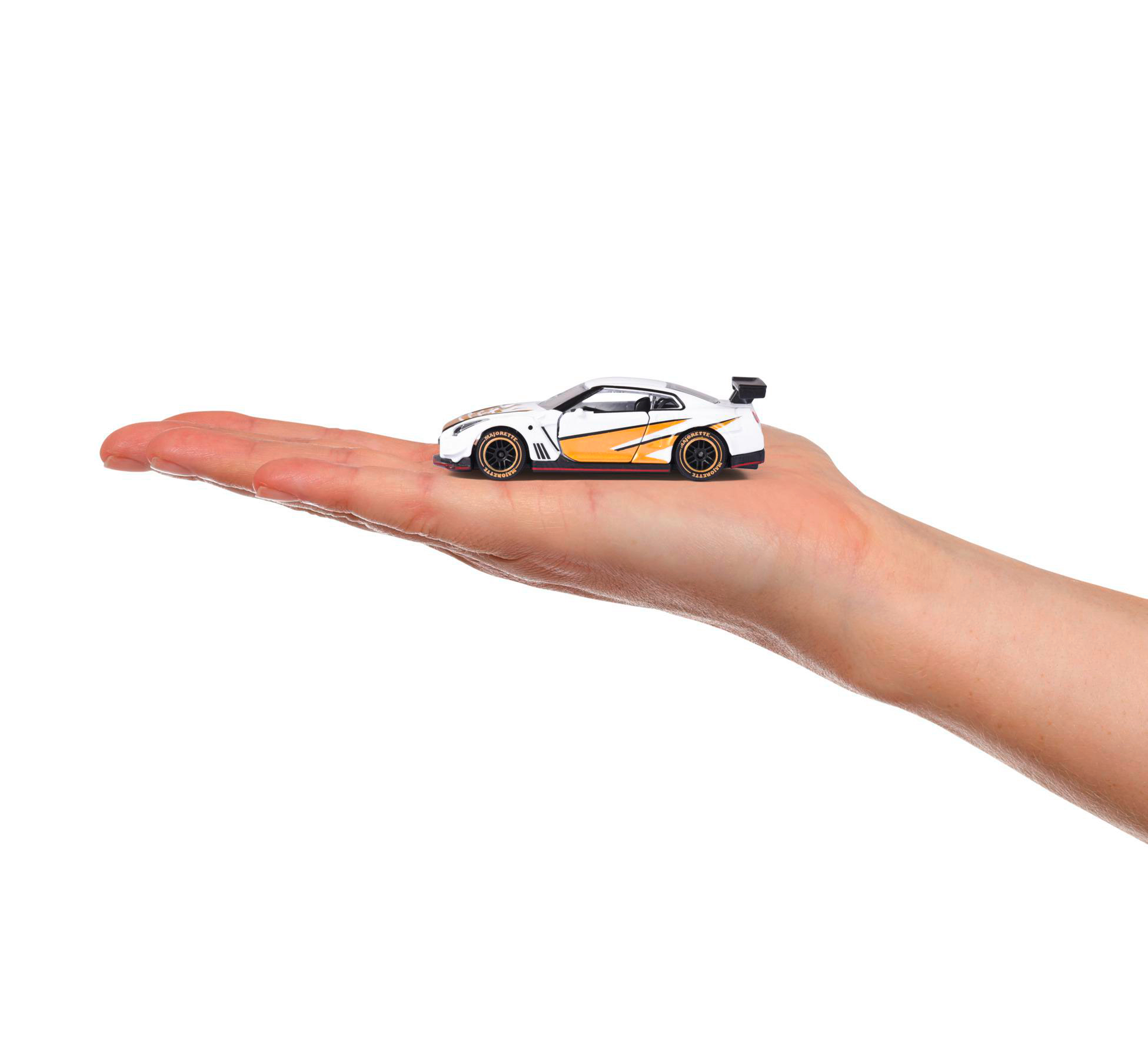 Ein Spielzeugauto wird in einer Hand gehalten, weißes Auto mit gelben Akzenten.