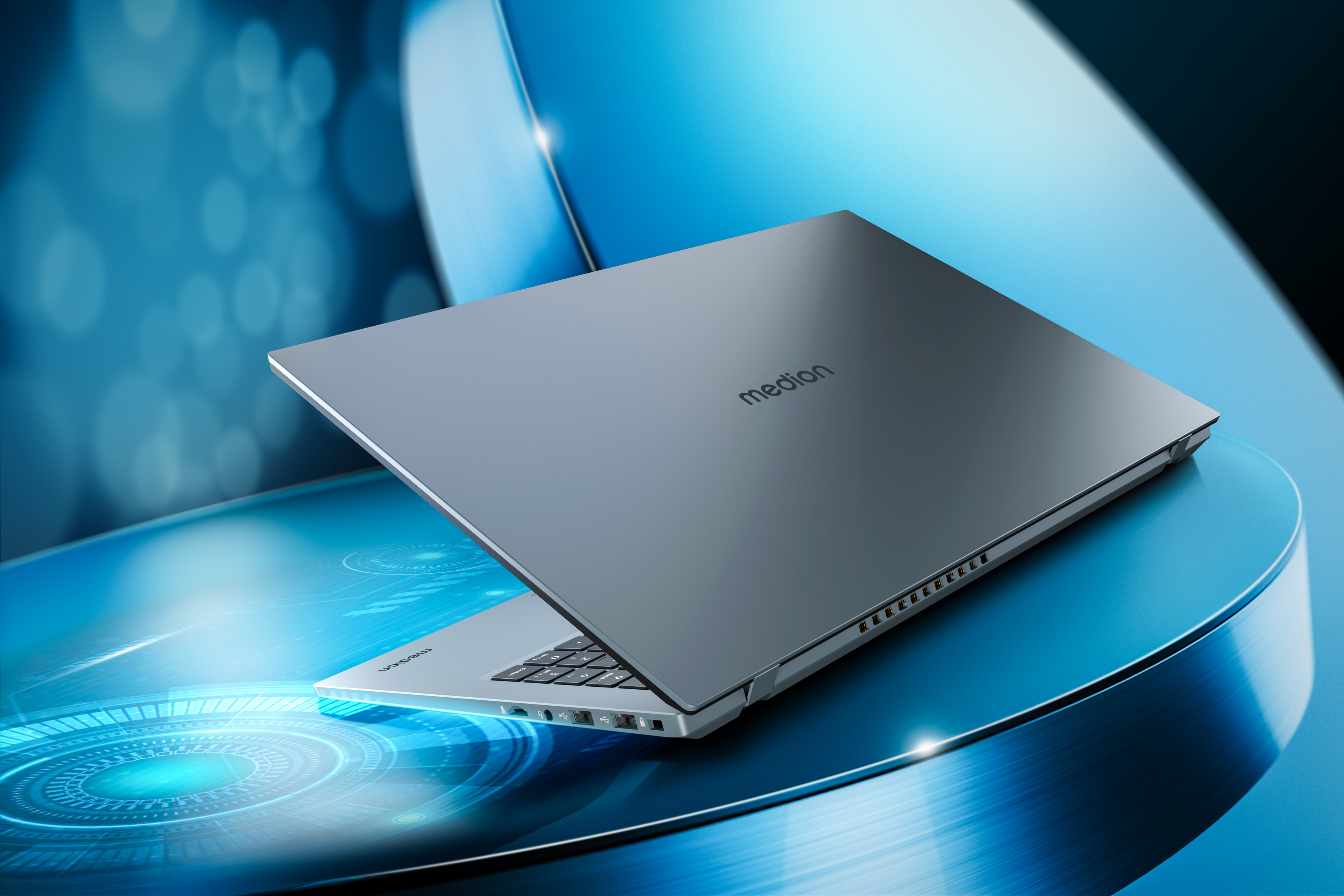 Laptop. Grau, offen auf blauer Oberfläche. Medion-Logo sichtbar. Hintergrund unscharf blau.
