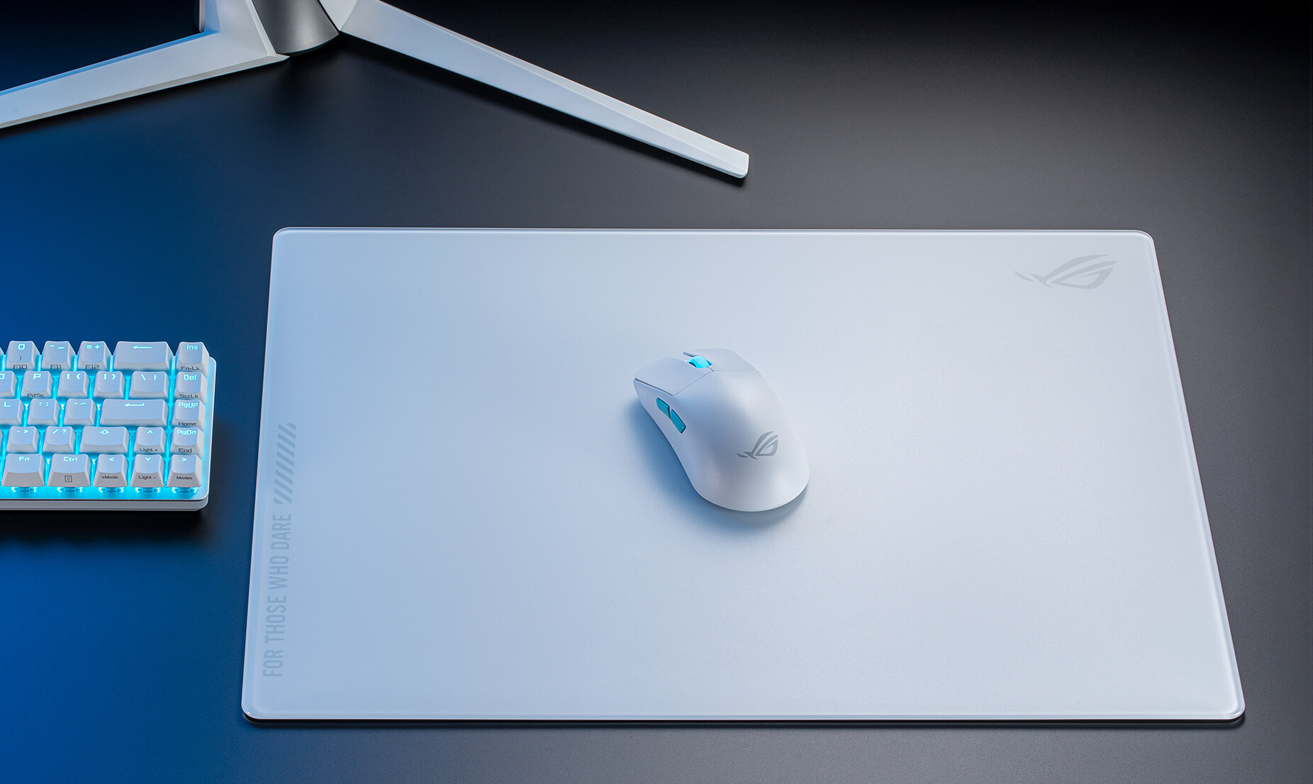 Souris et tapis de souris blancs, clavier sur une surface sombre. Logo ROG visible. Texte 'FOR THOSE WHO DARE'.