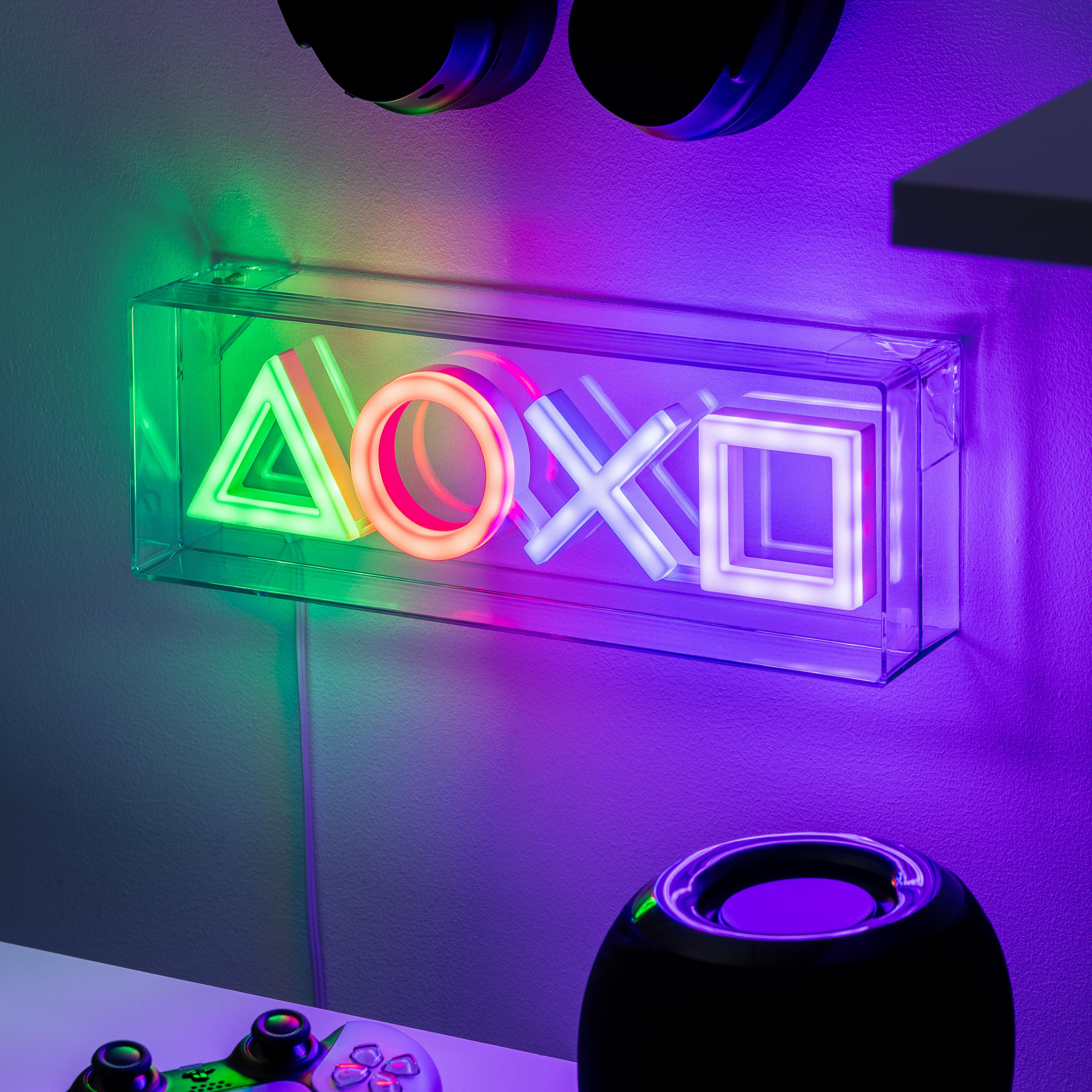 Ein Neon-Schild mit PlayStation-Symbolen in einer transparenten Box. Die Symbole sind grün, orange und weiß.