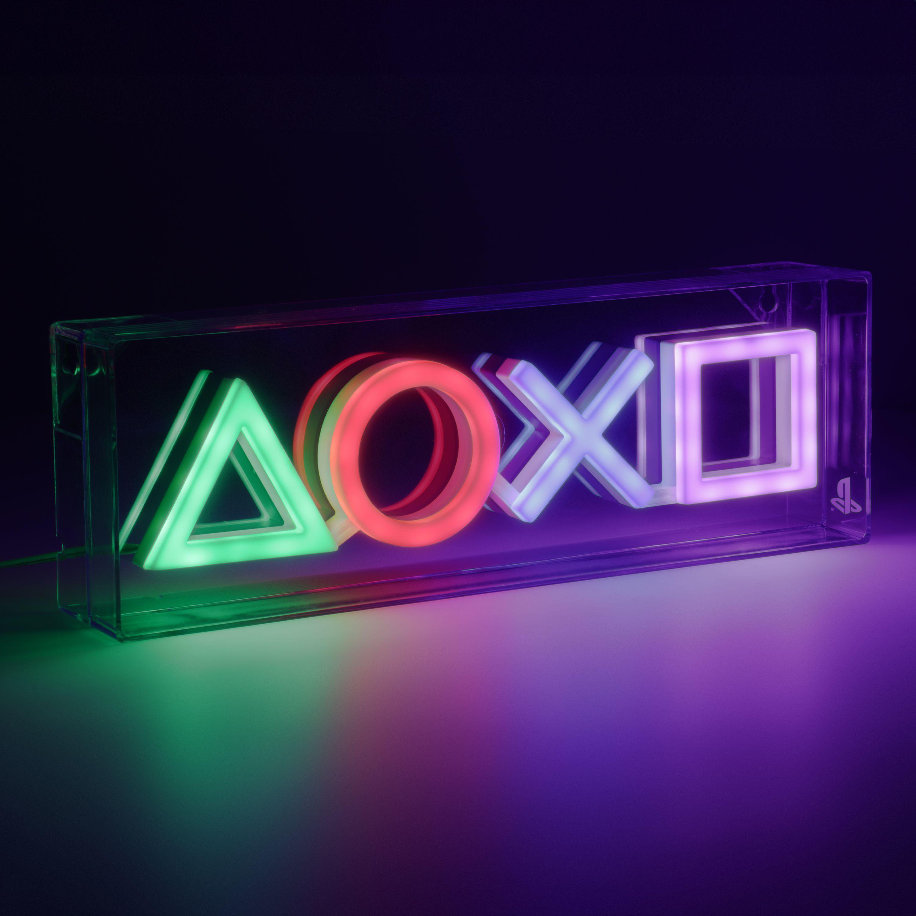 Eine transparente Plastikbox mit beleuchteten PlayStation-Controller-Symbolen auf lila Oberfläche.