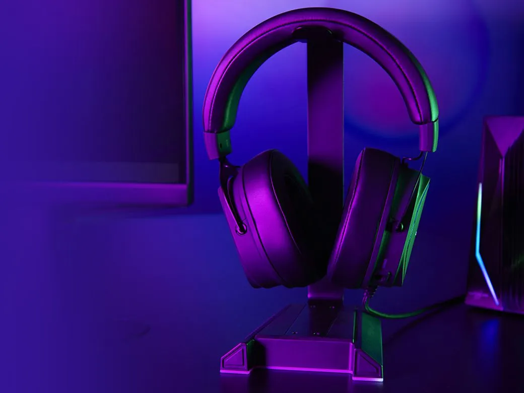 Schwarzer Gaming-Kopfhörer auf Ständer, beleuchtet von lila und grünen Lichtern.
