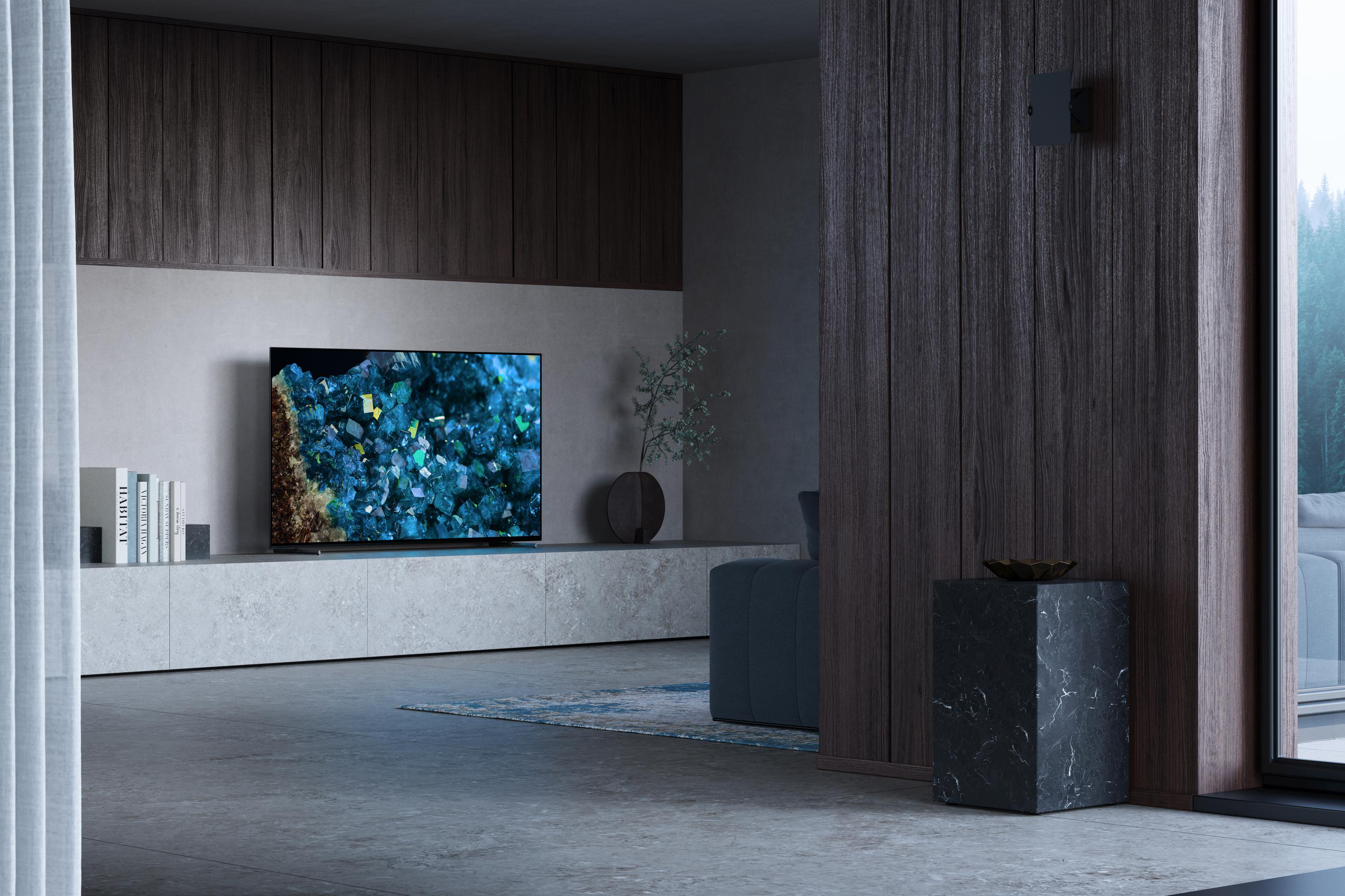 Ein modernes Wohnzimmer mit Fernseher auf einer Konsole, einem Beistelltisch aus Marmor und Blick in die Natur.
