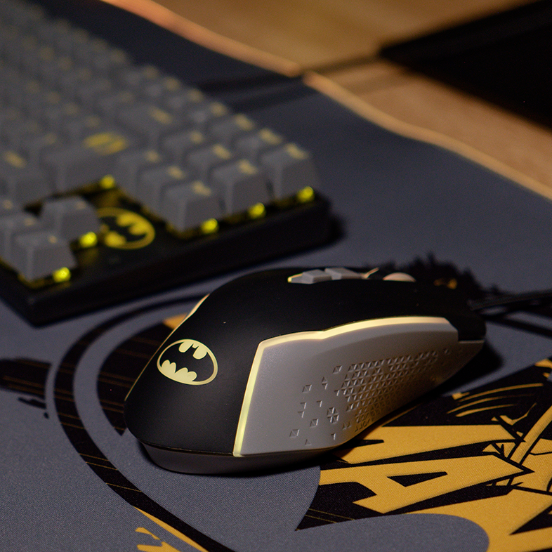 Egy Batman témájú egér egy egérpadon egy billentyűzet mellett. A billentyűzet Batman logóval rendelkezik.