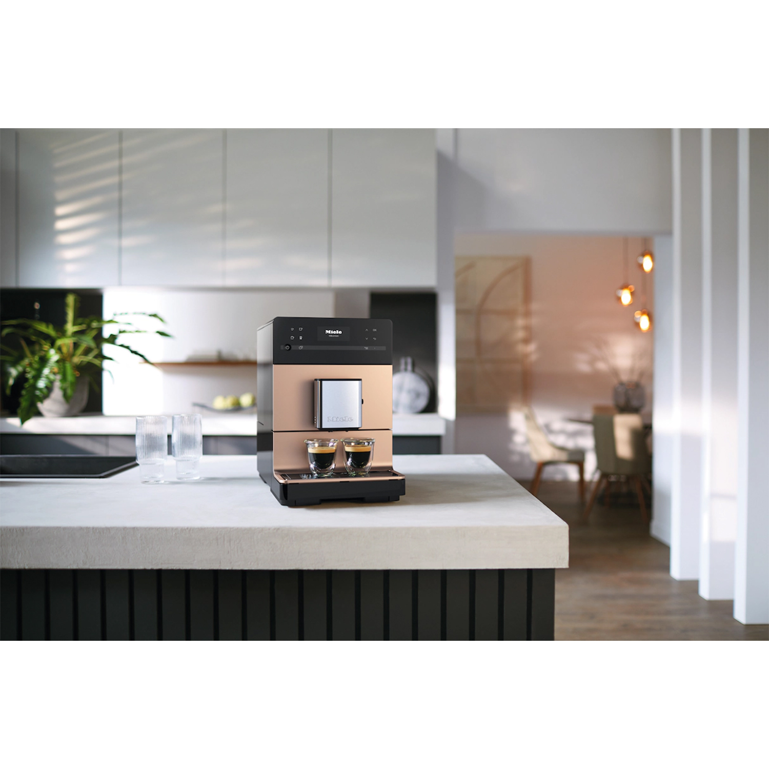 Una moderna macchina per il caffè con due tazzine di espresso su un piano di lavoro in una cucina luminosa.