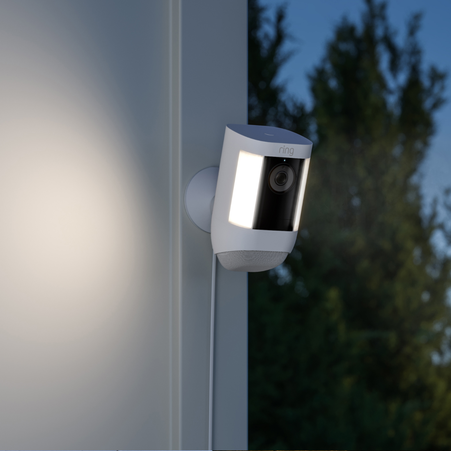 A security camera with a light mounted on a wall at night, illuminating the area.