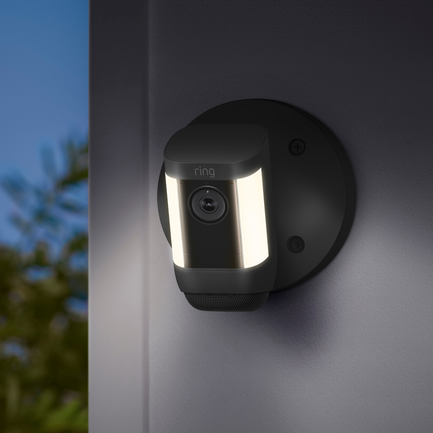 Black Ring security camera mounted on a wall with a light on.