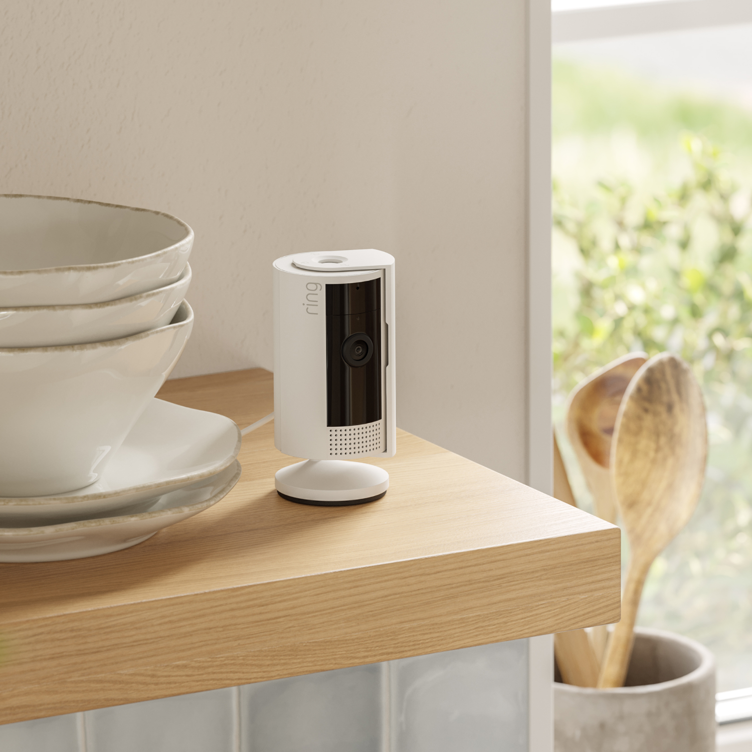 Witte Ring beveiligingscamera op een houten plank. Schalen en borden zijn zichtbaar.
