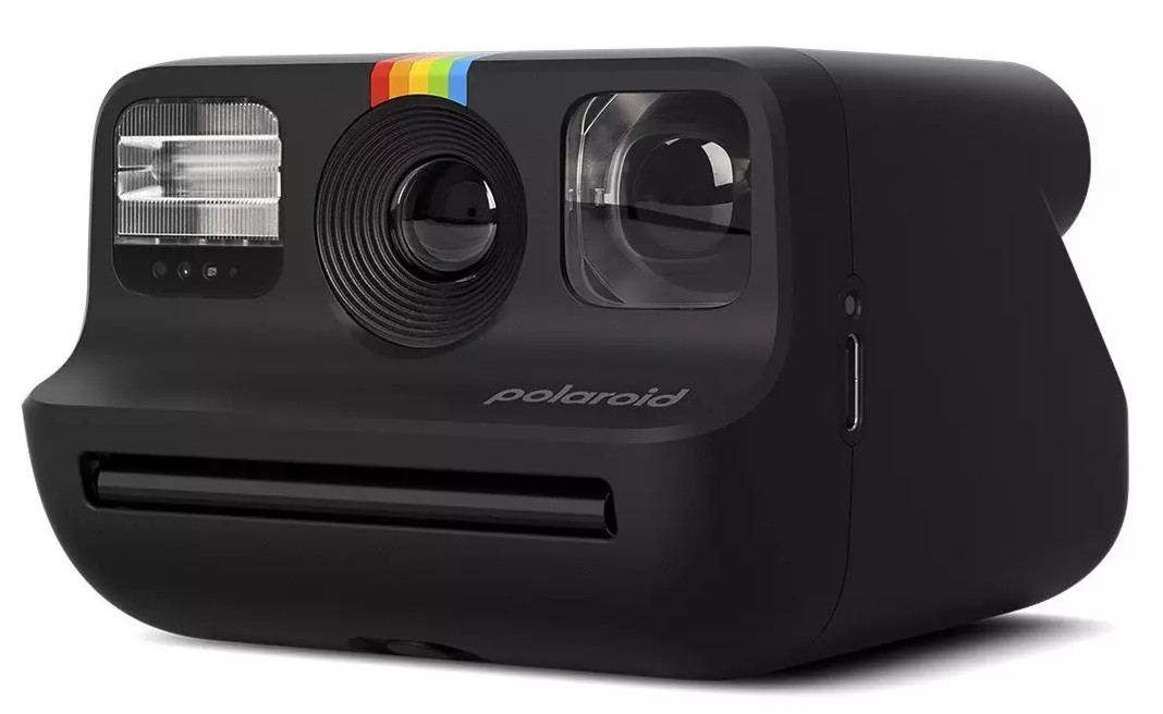 Czarny aparat Polaroid. Ma lampę błyskową, obiektyw i tęczowy pasek. Logo Polaroid znajduje się z przodu.
