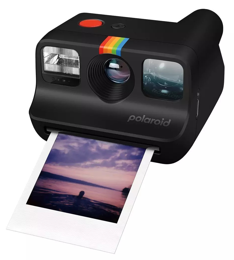Czarny aparat Polaroid z wysuwanym zdjęciem, tęczowy pasek, białe tło.
