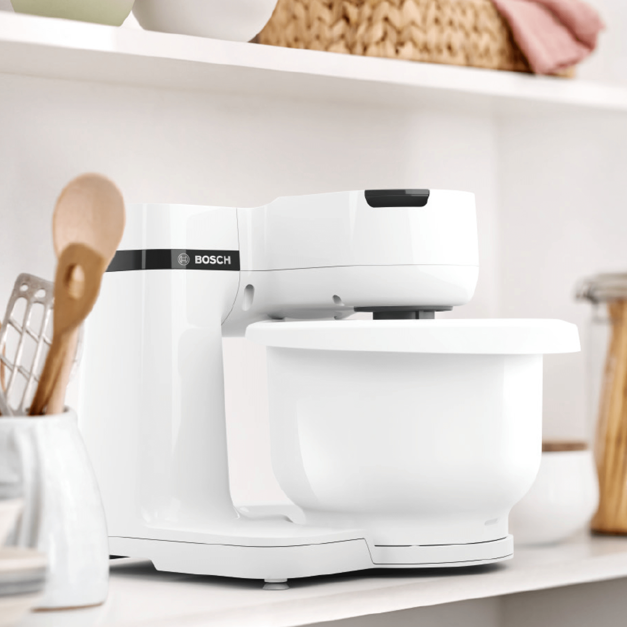 Weißer Küchenmixer auf einem Regal mit Küchenutensilien.