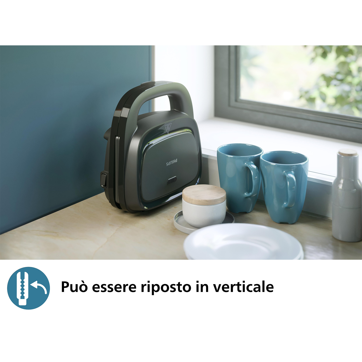 Una macchina per sandwich Philips grigio scuro su un bancone vicino a tazze, un piatto e un barattolo con coperchio di legno.