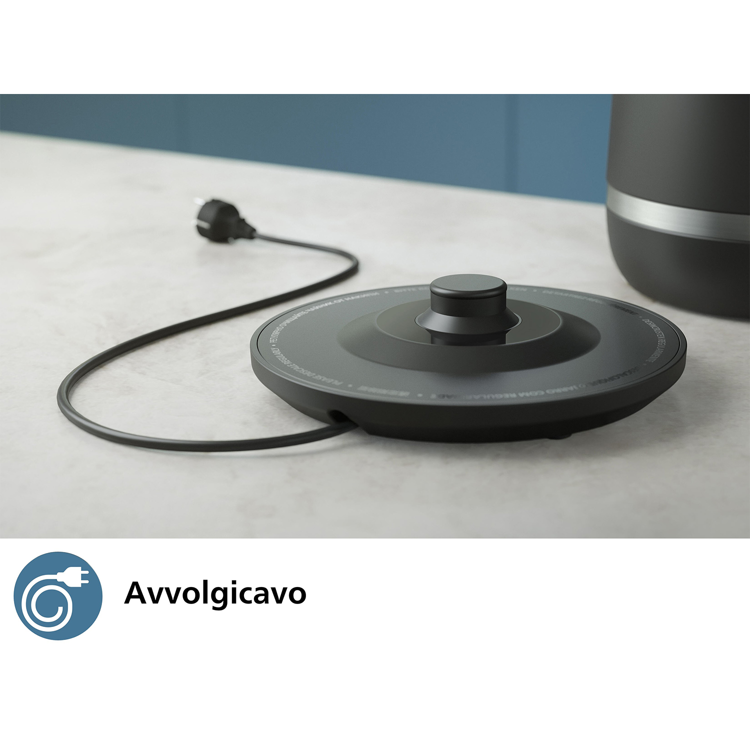 Coperchio nero del bollitore con cavo di alimentazione e bollitore, su superficie chiara.
