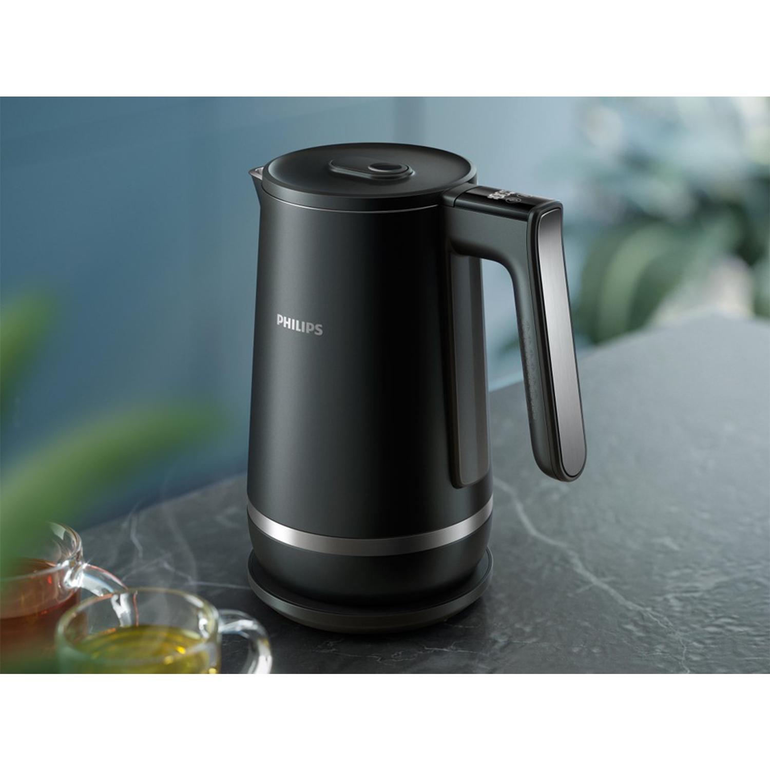 Bollitore elettrico Philips nero, manico a destra, con finiture argentate, su una superficie grigia.