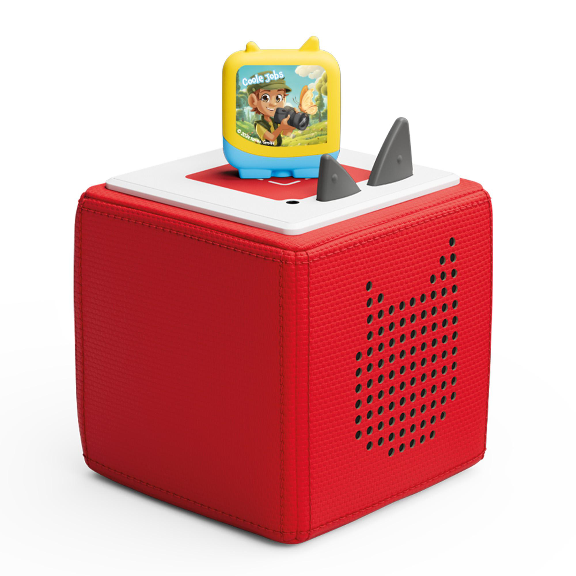 Roter, würfelförmiger Audioplayer mit Kinderspielzeug oben drauf. Lautsprecher und Bedienelemente sichtbar.