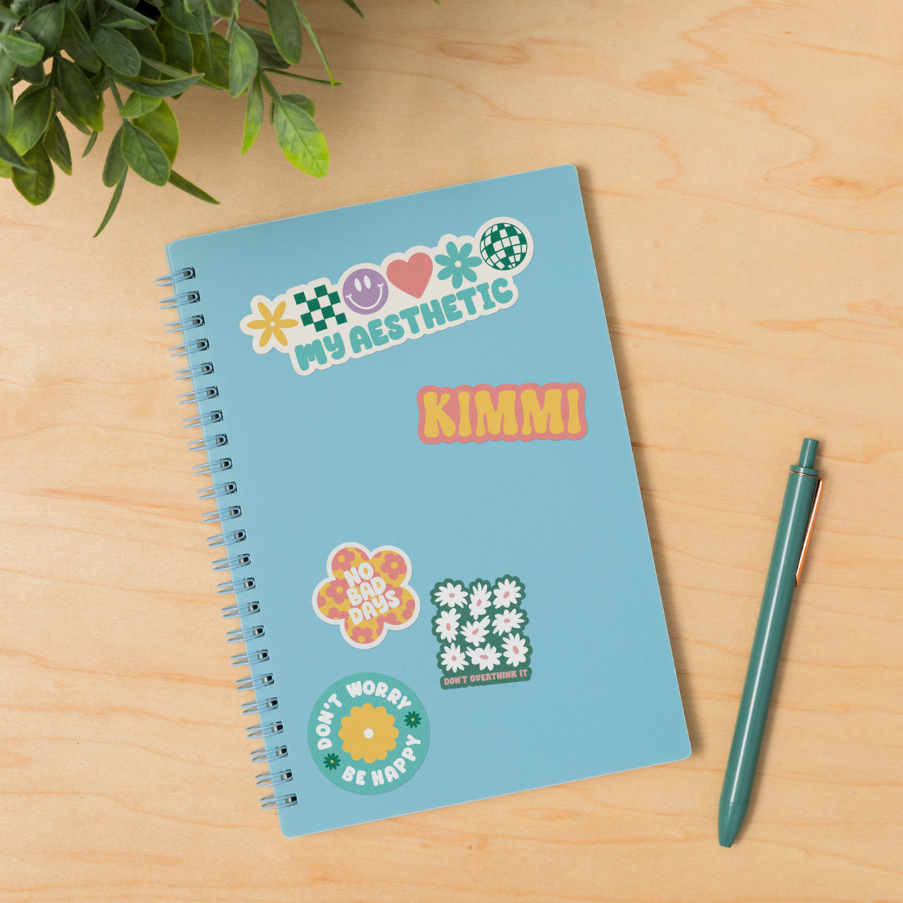 Ein blaues Notizbuch mit Aufklebern mit der Aufschrift 'My Aesthetic', 'Kimmi', 'No Bad Days' und 'Don't Overthink It'.
