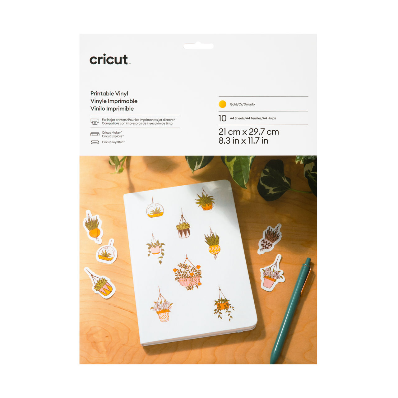 Ein weißes Blatt mit Pflanzenaufklebern und einem Stift auf einem Holztisch mit Cricut-Etikett.
