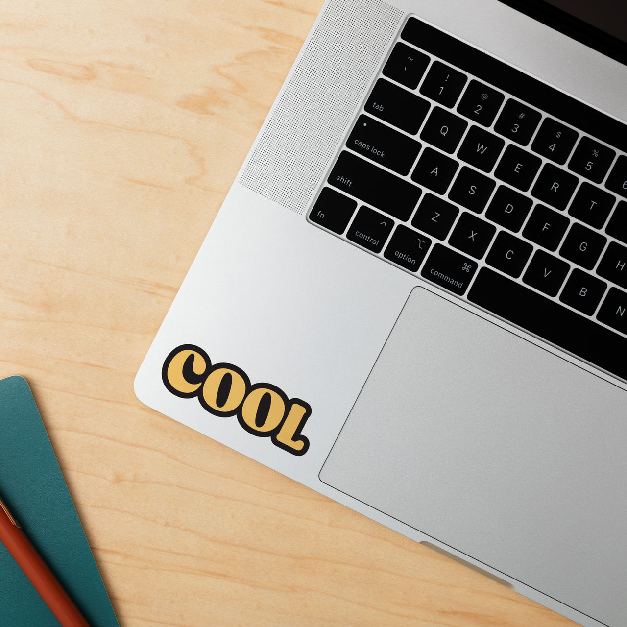 Ein Laptop mit einem Aufkleber mit der Aufschrift 'COOL' in der Ecke, auf einem Holztisch.