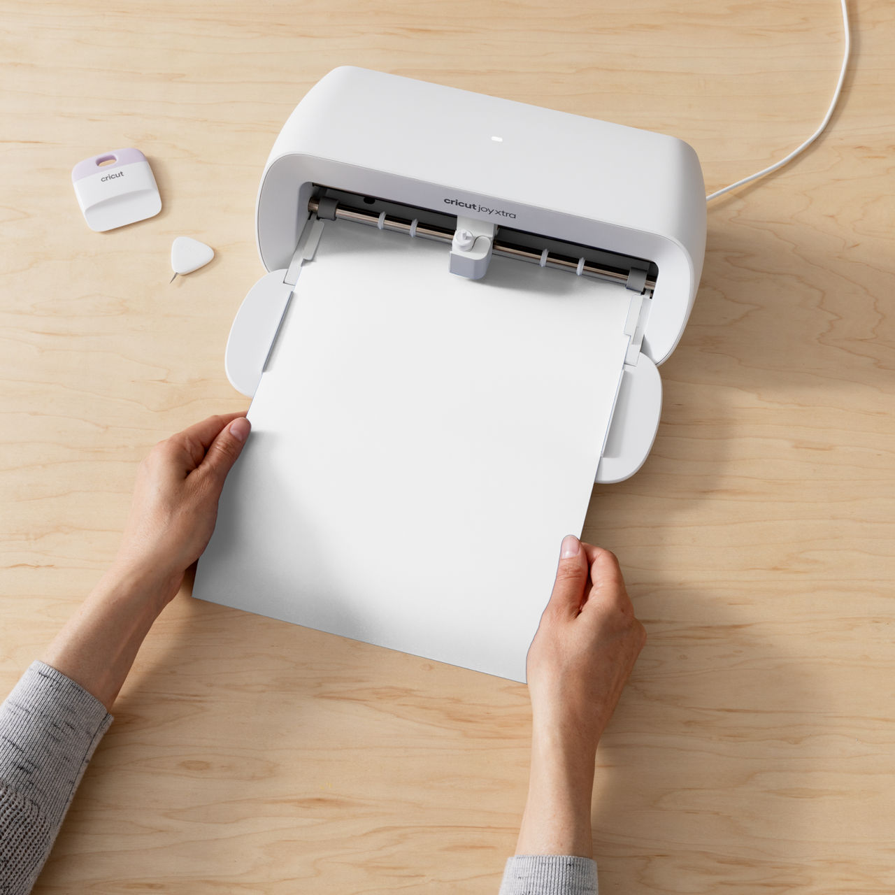 Personen halten Papier in der Nähe einer weißen Cricut-Maschine.