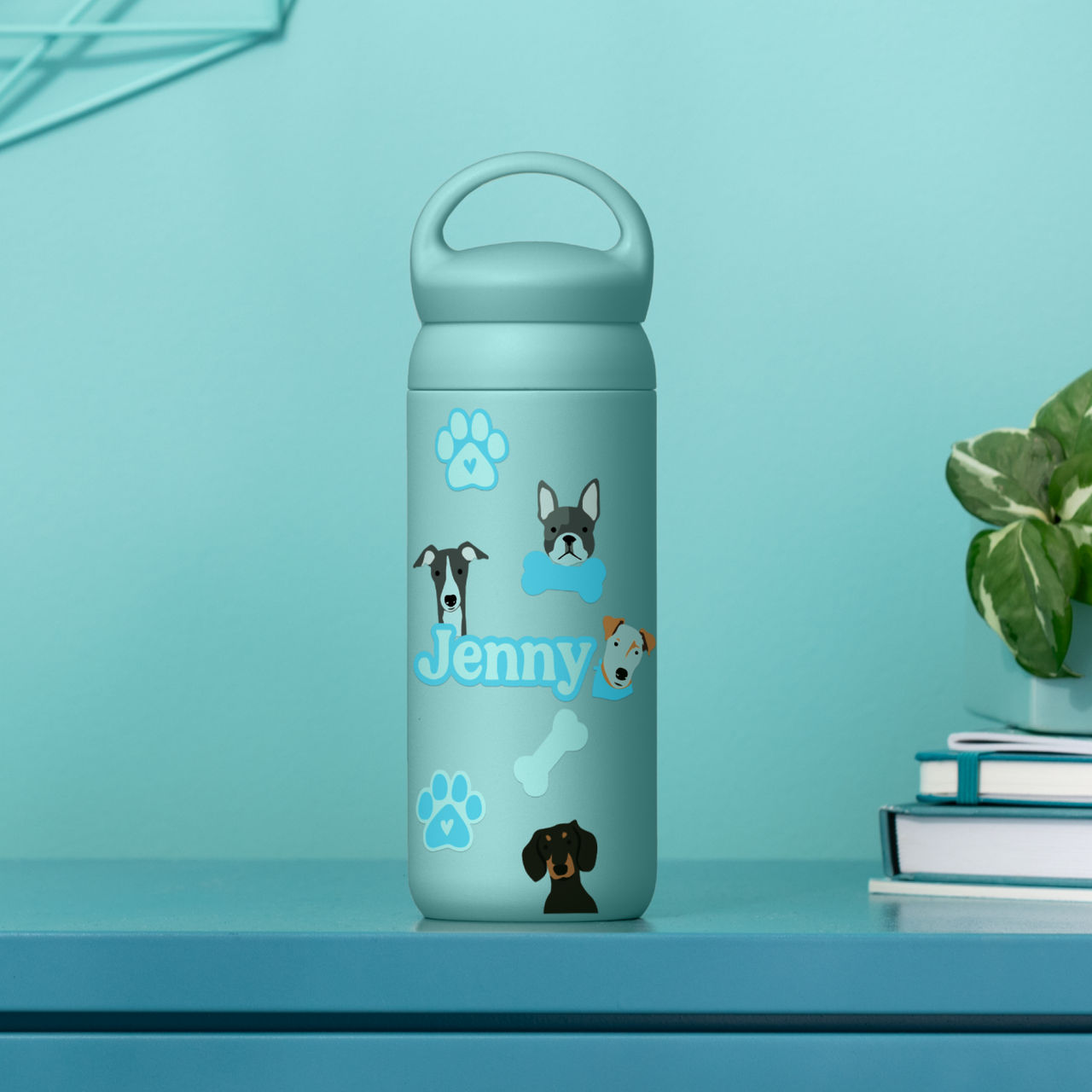 Eine hellblaue Wasserflasche mit Hundeillustrationen und 'Jenny' Schriftzug, vor einem türkisfarbenen Hintergrund.