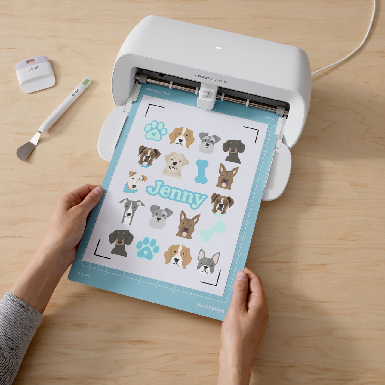 Frau hält eine Cricut Joy Xtra, Schneidemaschine, mit Hunde-Design.