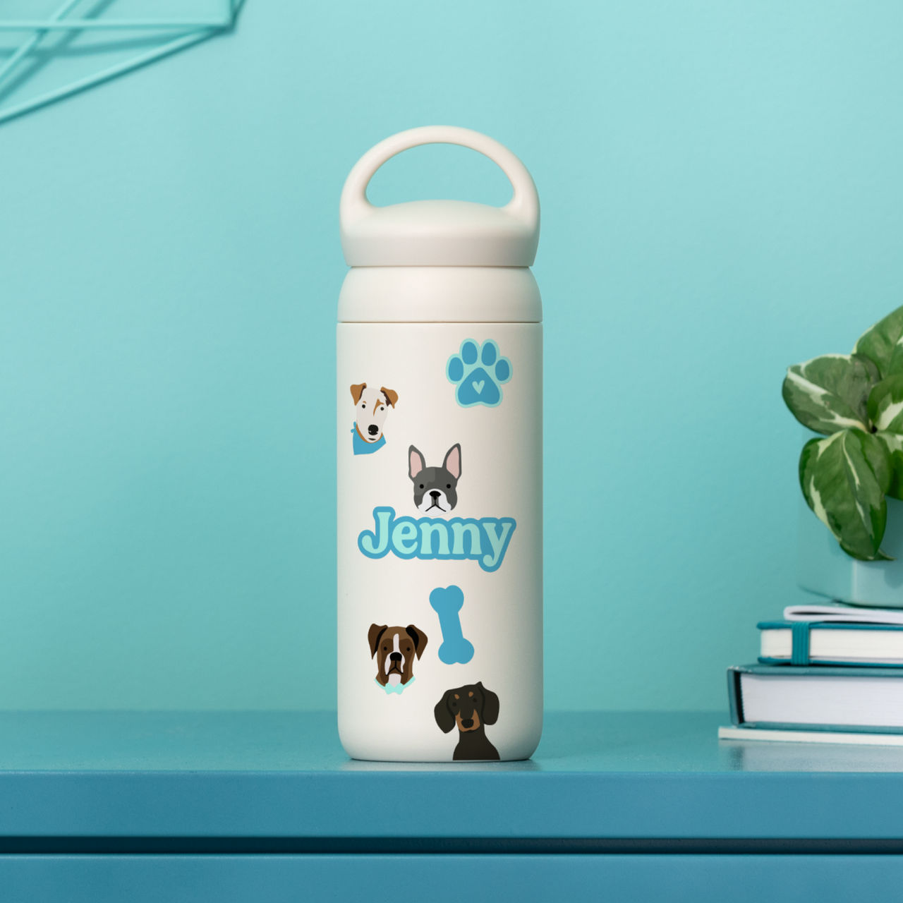 Weiße Wasserflasche mit Hundeillustrationen und dem Namen 'Jenny'. Die Flasche steht auf einem blauen Tisch.