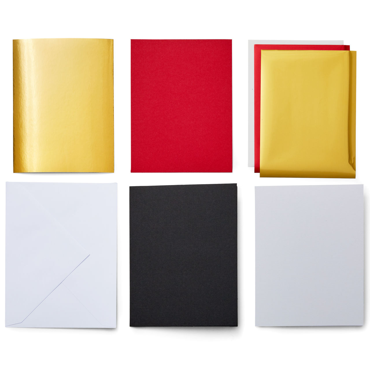 Sechs farbige Papierquadrate: Gold, Rot, Gold auf Rot, Weiß, Schwarz und Weiß. Schatten deuten auf eine Oberfläche hin.