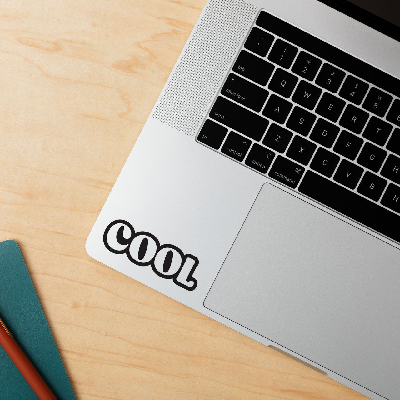 Laptop-Tastatur mit einem "COOL"-Aufkleber auf dem Trackpad.