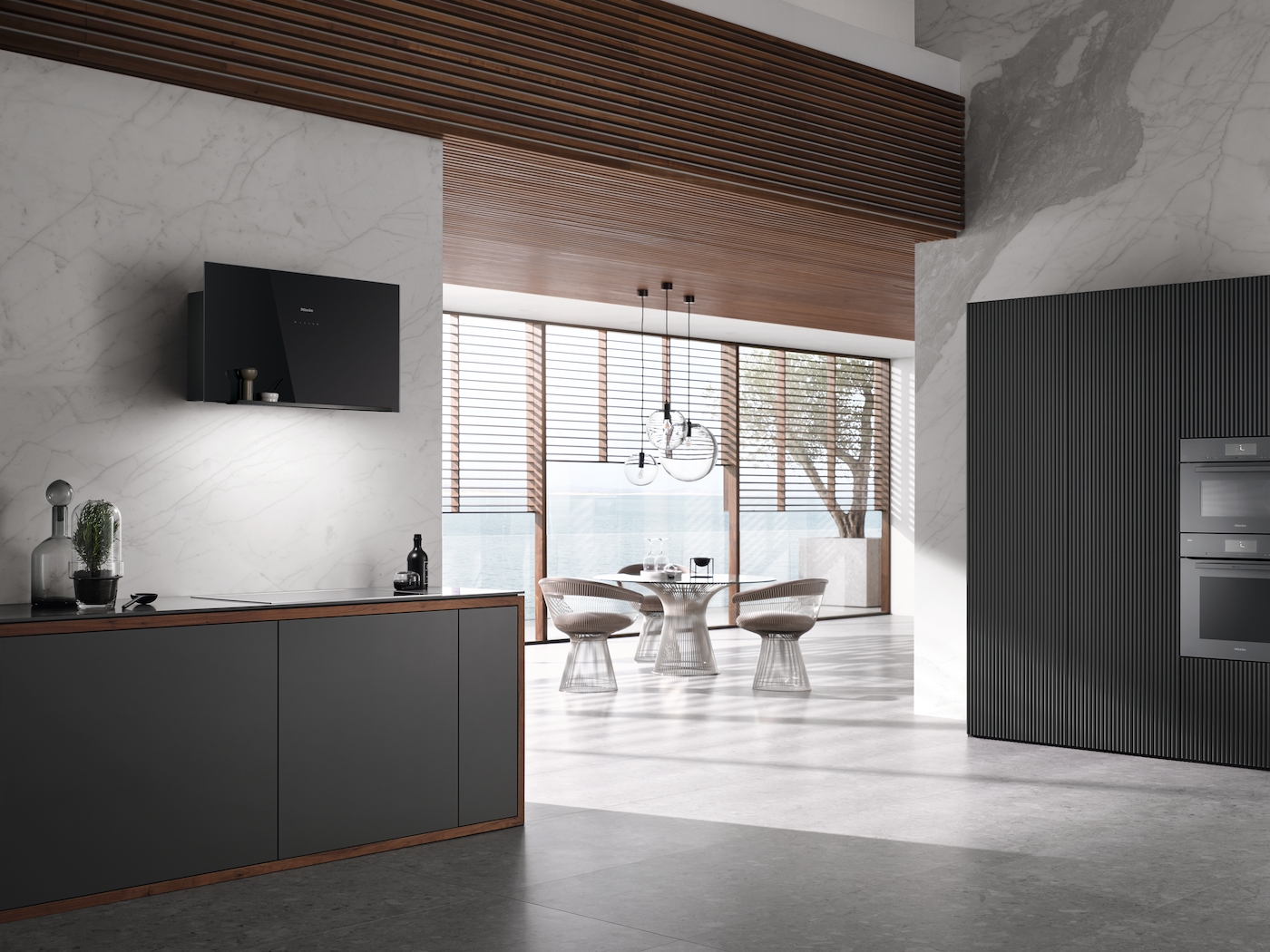 Modernes Kücheninterieur mit schwarzer Dunstabzugshaube, Esstisch und dunkelgrauen Schränken.