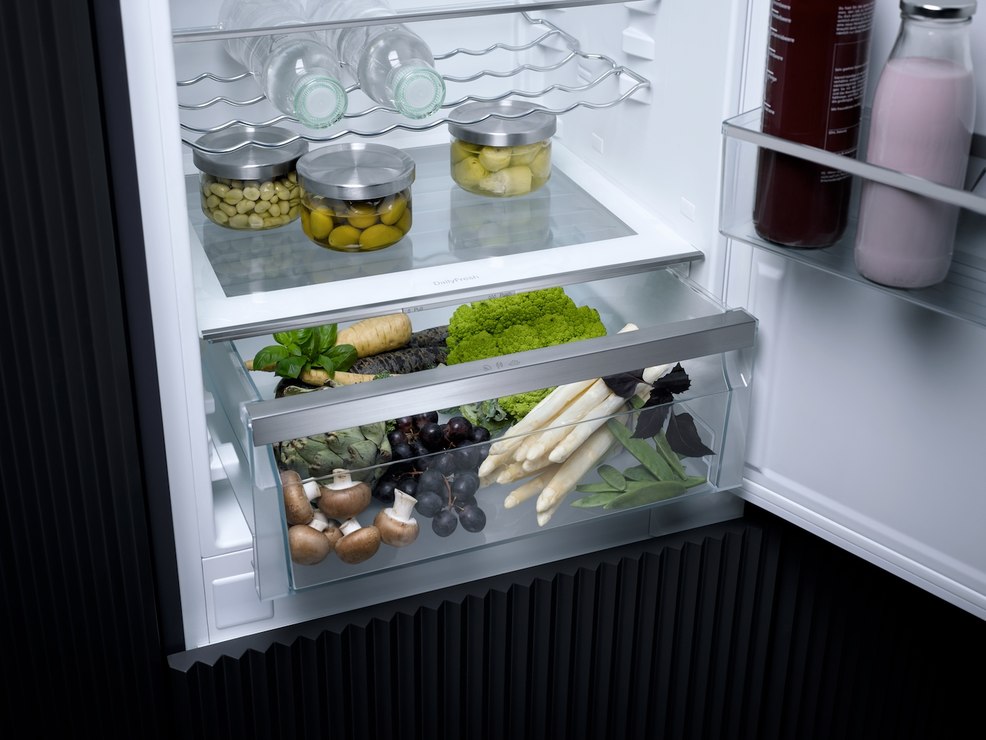 Ein Kühlschrank mit Gemüse und Gläsern darin.