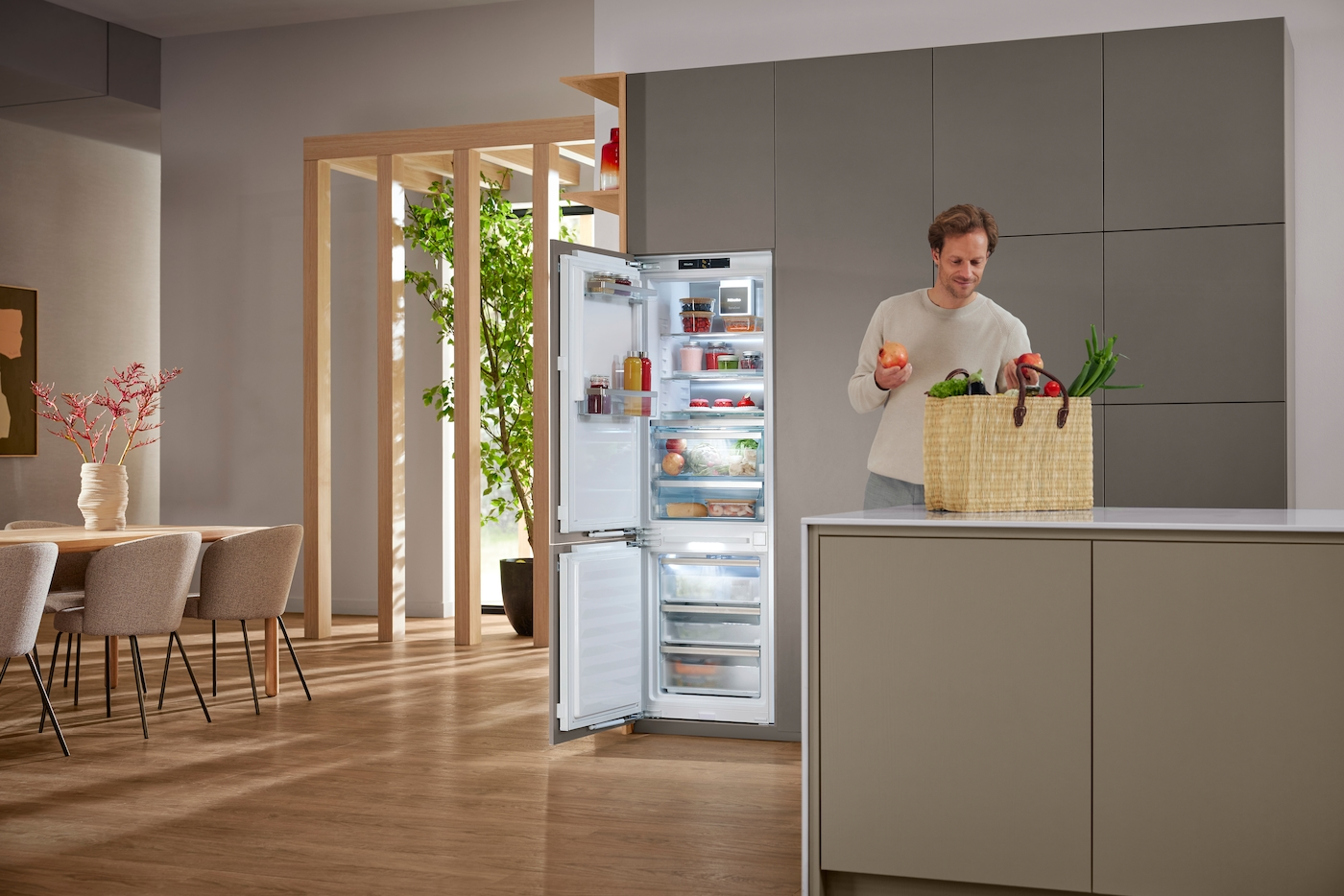 Mann stellt Obst und Gemüse in offenen Kühlschrank.
