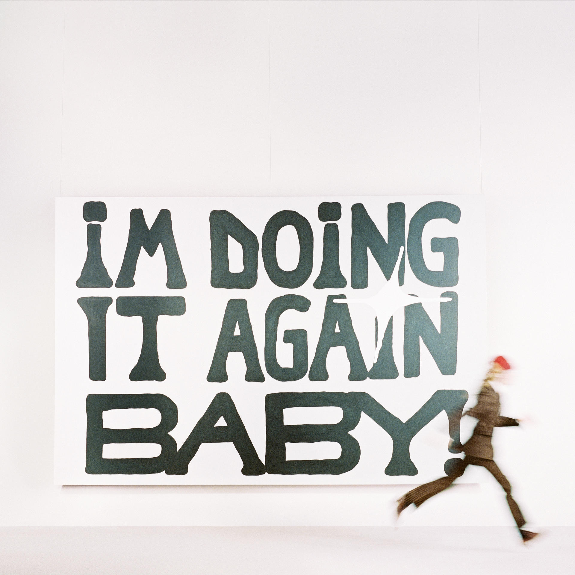 Eine Person rennt an einem Schild vorbei mit der Aufschrift: I'M DOING IT AGAIN BABY. Weißer Hintergrund.