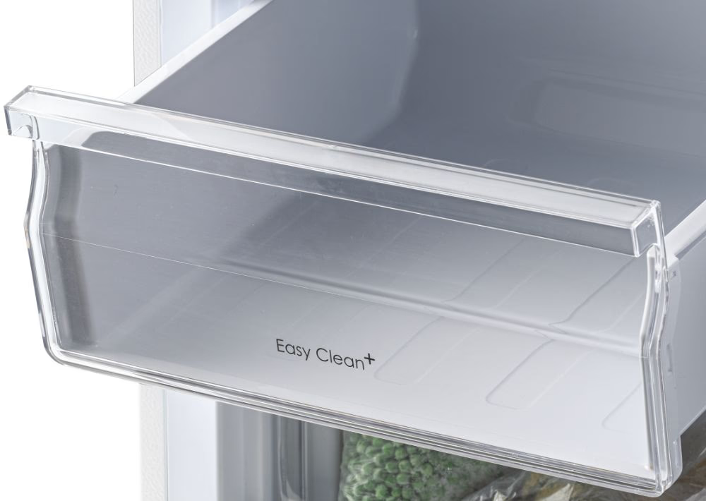 Átlátszó hűtőfiók 'Easy Clean+' felirattal, fagyasztott zöldborsót mutatva.