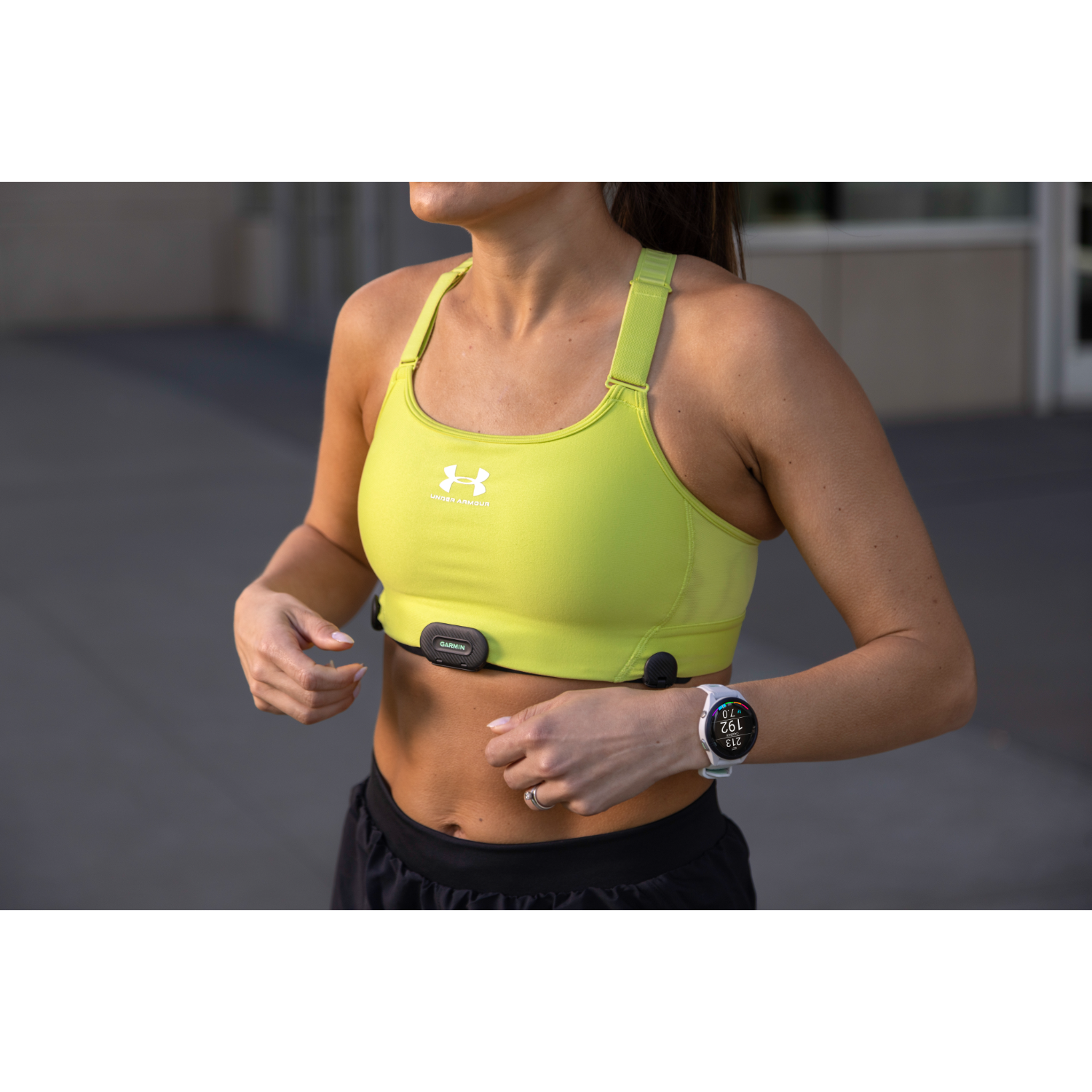 Vrouw die een limoengroene sportbeha draagt met een Garmin-horloge.