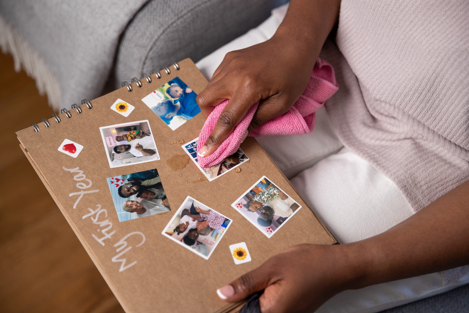 A person is cleaning a scrapbook with photos. The scrapbook says "My First Year" and has stickers.
