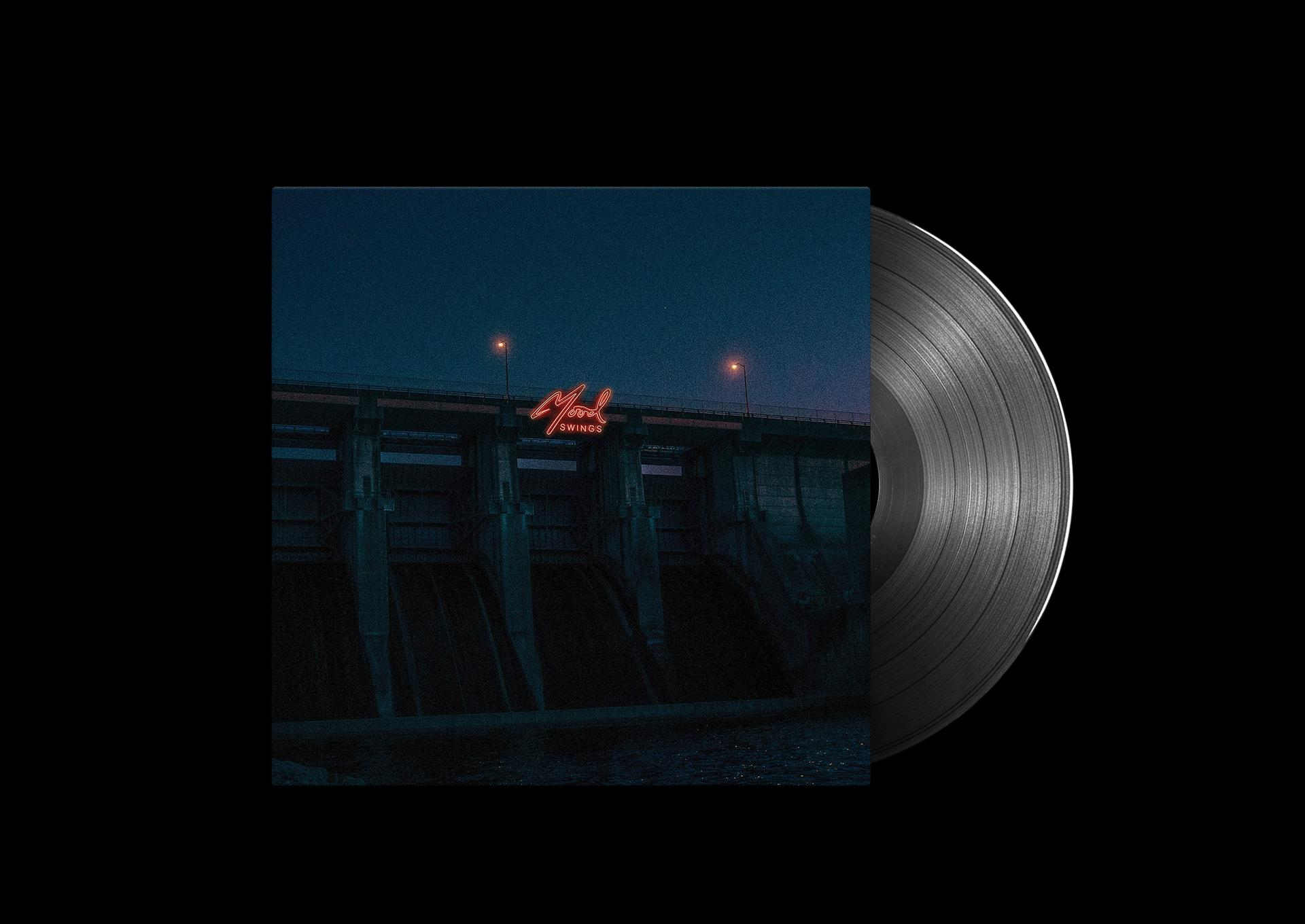 Eine Vinylplatte mit einem Cover, das nachts einen Staudamm mit dem Wort 'Mood Swings' zeigt.