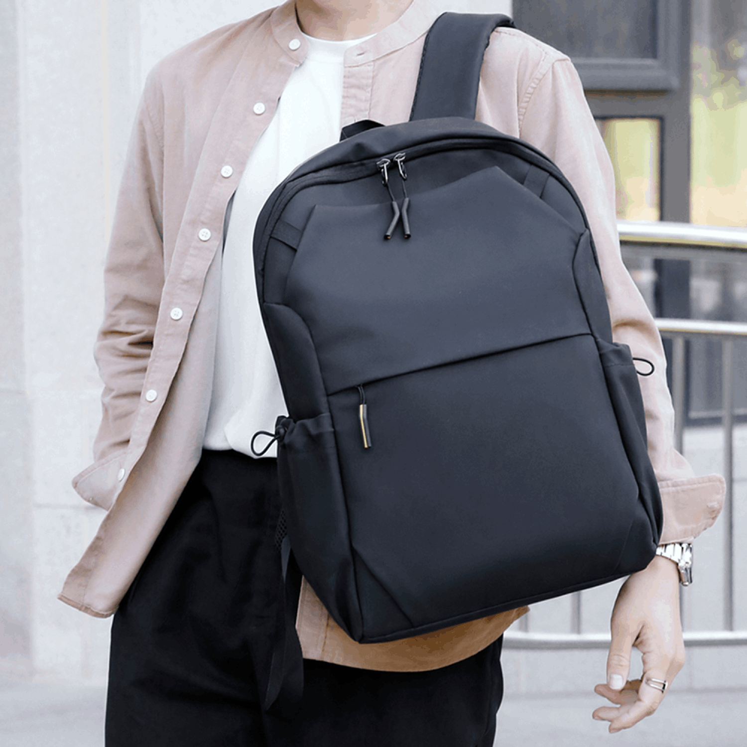 Persona con camisa marrón claro y pantalones negros con una mochila negra.