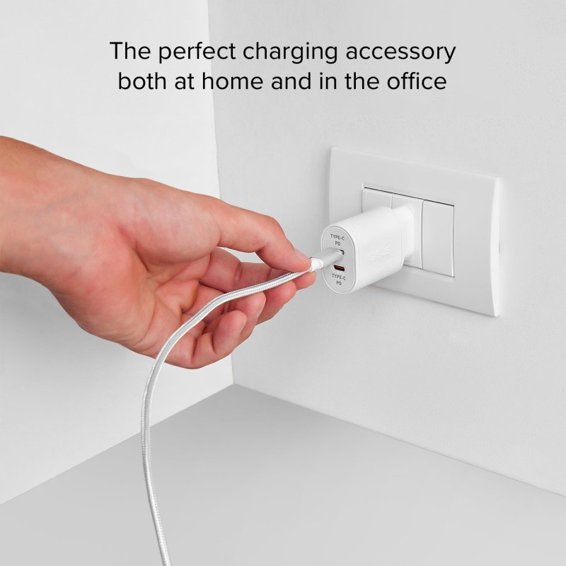 Eine Hand steckt ein weißes USB-Ladegerät in eine Steckdose.