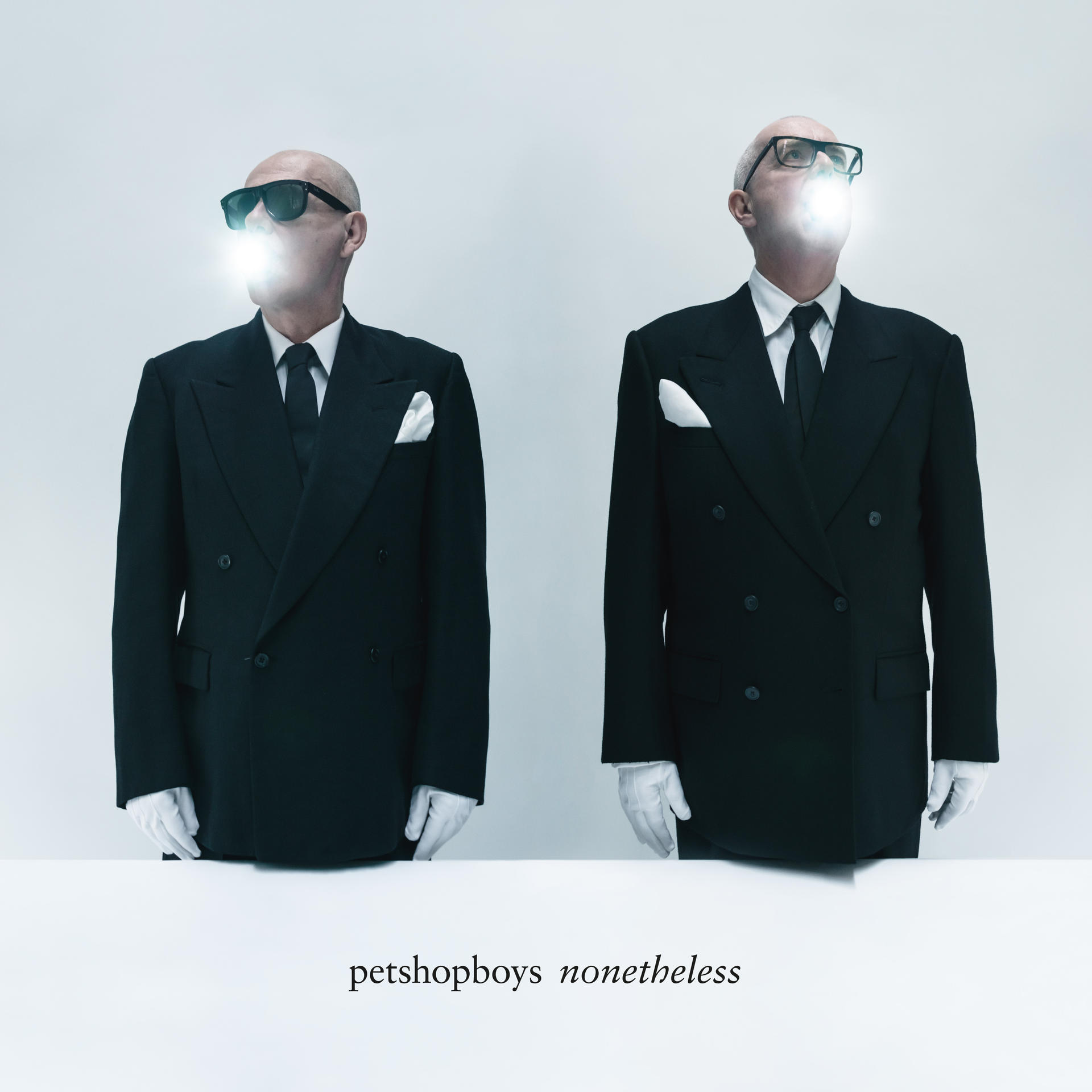 Két férfi fekete öltönyben, fehér kesztyűben és napszemüvegben, világító szájjal. Alatta a 'petshopboys nonetheless' felirat.